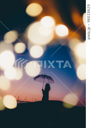 夕暮れの自然の中で傘を持って佇む女性の写真 夕暮れの自然の中で傘を持って佇む女性の写真 96018629