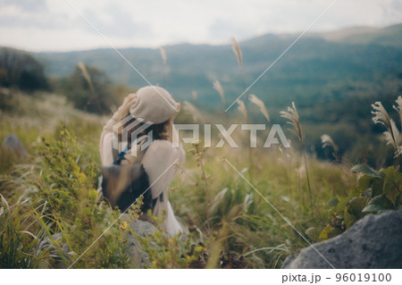 自然の中にカメラを持って佇む女性の写真 96019100