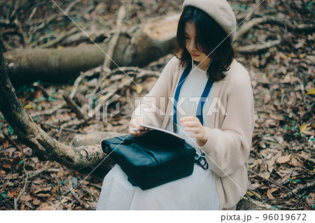 自然の中で音楽を聴きながら創作活動をする女性の写真 96019672