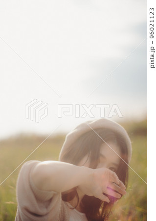 夕暮れの自然の中で佇む女性の写真 96021123