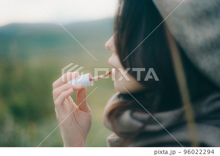 自然の中に佇みグロスを塗る女性の写真 自然の中に佇みグロスを塗る女性の写真 96022294