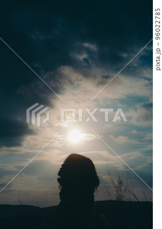自然の中で音楽を聴く女性のシルエットの写真 96022785