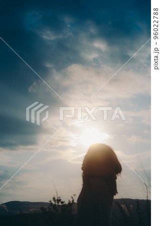 自然の中で音楽を聴く女性のシルエットの写真 96022788