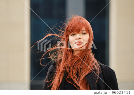 Street portrait of a happy young red-haired woman 96023411