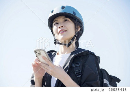フードデリバリーイメージ　届け先をスマホでチェックする配達員女性 96023413