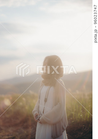 夕暮れの自然の中でカメラを持つ女性の写真 夕暮れの自然の中でカメラを持つ女性の写真 96023747