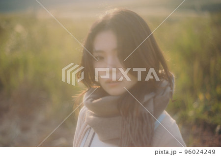 夕暮れの自然の中に佇む女性の写真 96024249