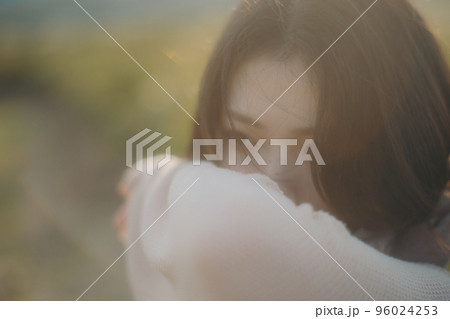 夕暮れの自然の中に佇む女性の写真 96024253