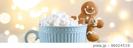 banner of a blue cup of winter hot drink with marshmallows and gingerbread man on a white wooden background with bokeh. banner of a blue cup of winter hot drink with marshmallows and gingerbread man on a white wooden background with bokeh. 96024519