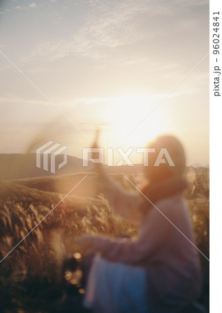 夕暮れの自然の中で音楽を聴く女性の写真 96024841