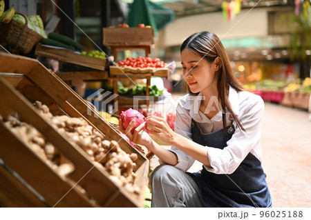 Image of female seller wearing apron arranging organic fruit on her stall at an open street market. Farmers market concept Image of female seller wearing apron arranging organic fruit on her stall at an open street market. Farmers market concept 96025188