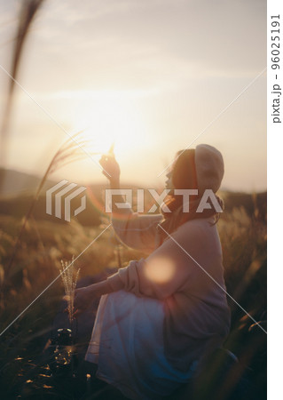 夕暮れの自然の中で音楽を聴く女性の写真 夕暮れの自然の中で音楽を聴く女性の写真 96025191