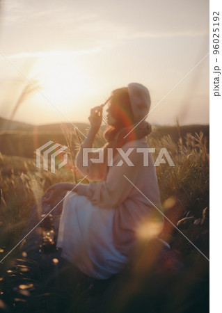 夕暮れの自然の中で音楽を聴く女性の写真 96025192