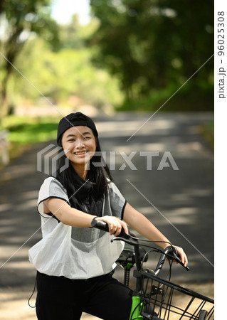 Portrait of smiling teenage girl with bike in the city park. People and outdoor activity concept 96025308
