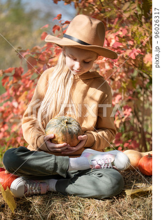 Girl in the hay with pumpkins Girl in the hay with pumpkins 96026317