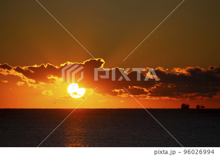 Dawn sun go behind cloud over sea horizon during dawn. Sunbeams, sun rays. Dawn sunrise dawning on sea. Black silhouettes of sea and clouds. Sky sea landscape. Seascape Fast moving clouds 96026994