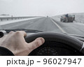 view of the driver hand behind the wheel of a car that passes by a stopped car 96027947