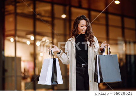 Young woman with shopping bags near mall. Spring Style. Consumerism, purchases, shopping, lifestyle. 96029023