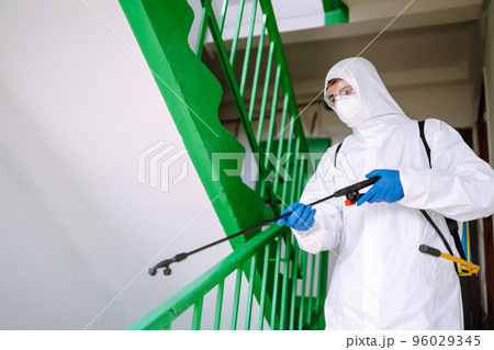 Man in Hazmat suit, protective gloves and goggles use sprayer equipment disinfect the entrance. 96029345