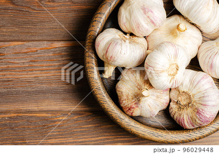 Garlic in a wooden plate. Brown wooden background. Copy space. 96029448