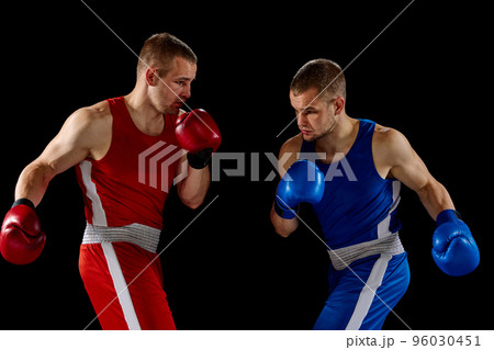 Male professional boxers in blue and red sports uniform practicing punch isolated on dark background. Concept of sport, competition, training, energy. 96030451