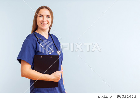Female nurse or doctor with clipboard against a blue background Female nurse or doctor with clipboard against a blue background 96031453