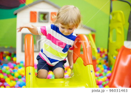 Little boy riding on slide at indoor play center 96031463