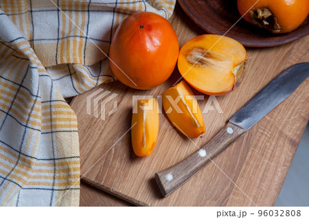 Whole ripe persimmon and sliced fruit on a wooden background.. 96032808