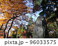 青空の下の紅葉した木と石碑 96033575