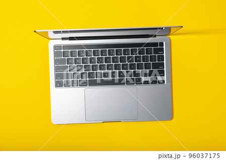 Open laptop on yellow background, top view 96037175