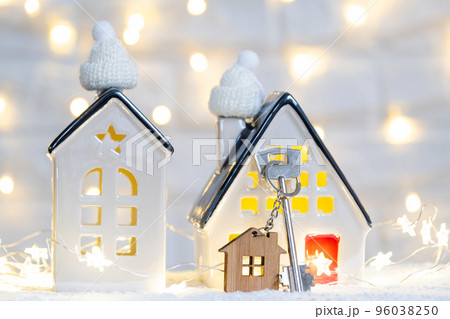 Key to the house with a keychain on a cozy home with a Christmas decor. A gift for New Year, Christmas. Building, design, project, moving to new house, mortgage, rent and purchase real estate 96038250