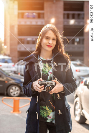 Portrait of a pretty young tourist taking photographs with vintage retro camera Portrait of a pretty young tourist taking photographs with vintage retro camera 96038434