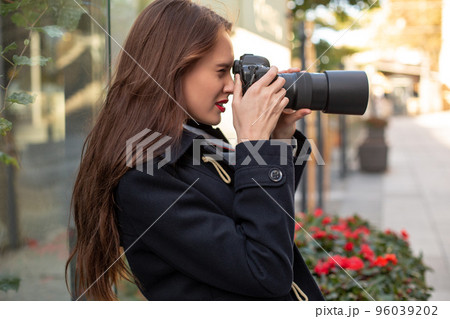 Happy woman on vacation photographing with camera on the city street Happy woman on vacation photographing with camera on the city street 96039202