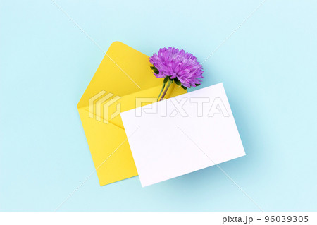 White blank card, yellow envelope and purple flower on blue background. Minimal style. Top view Flat lay Mockup 96039305