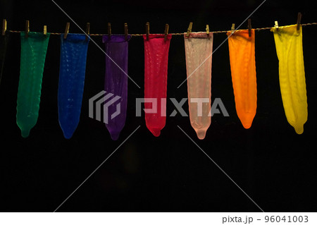 many contraceptives condoms hanging on a rope isolated on black background 96041003