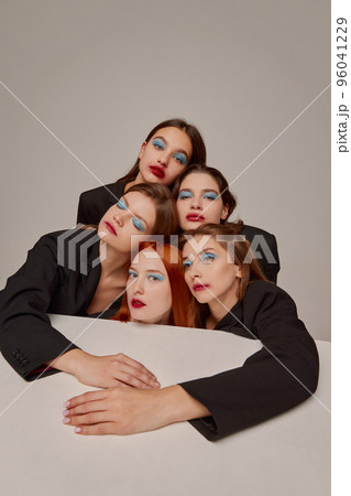 Portrait of young beautiful women in black jackets with red lipstick, blue eyeshadow makeup posing over grey background 96041229