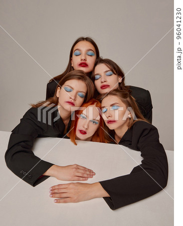 Portrait of young beautiful women in black jackets and red lipstick makeup posing over grey background. 90s look Portrait of young beautiful women in black jackets and red lipstick makeup posing over grey background. 90s look 96041230