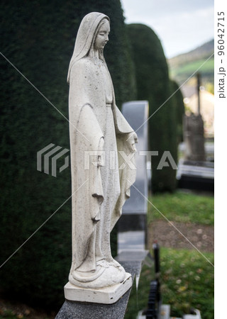 View of the virgin mary statue on tomb in a cemetery View of the virgin mary statue on tomb in a cemetery 96042715