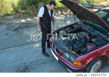 mature man fixing a fault in his car engine with tools mature man fixing a fault in his car engine with tools 96043778