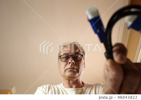 mature man taking a cable from a drawer at home 96043822