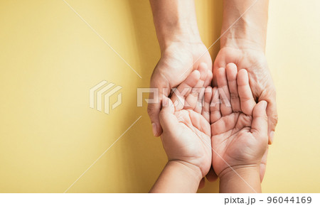 Close up hands children on adult mother hand, Top view person kid stack mom palms, Parents and little kid holding empty hands together isolated on yellow background, Family day care concept 96044169
