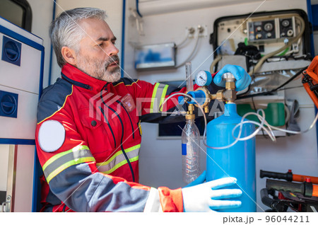 Concentrated paramedic preparing the breathing apparatus for oxygen therapy 96044211