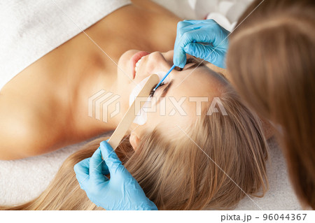 Young woman undergoing eyelash lamination in salon Young woman undergoing eyelash lamination in salon 96044367