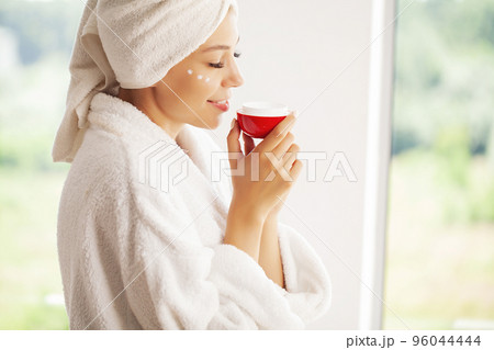 Studio shot of beautiful young woman applying moisturizer cream onto her face 96044444