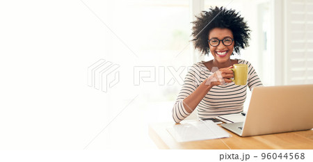 Nothing like a cup of comfort to start the day. Cropped portrait of a young woman drinking coffee while working on her laptop at home. Nothing like a cup of comfort to start the day. Cropped portrait of a young woman drinking coffee while working on her laptop at home. 96044568
