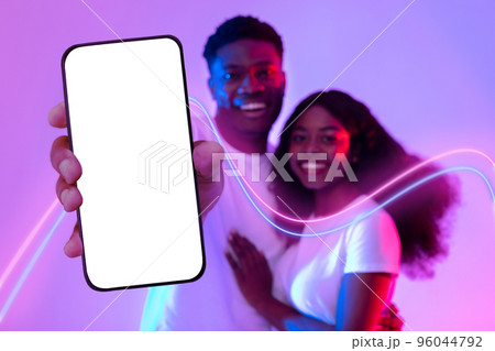 Happy black lovers hugging and showing smartphone with empty screen 96044792