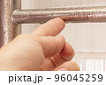 the hand touches the condensate on the heated towel rail. Close-up 96045259