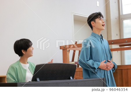 ピアノを弾きながら教えるボイストレーナーと発声練習する男性_1 ピアノを弾きながら教えるボイストレーナーと発声練習する男性_1 96046354