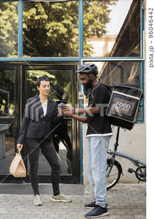 Workplace food delivery, smartphone pos terminal payment, smiling woman paying for lunch with mobile wallet. Courier delivering restaurant takeaway meal employee in front of office building 96046442