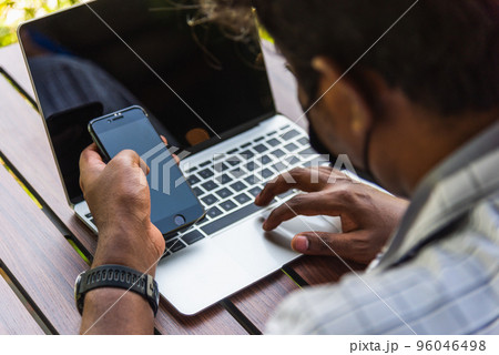 Happy Asian hand black man person working with laptop computer and reading message from modern smart phone blank screen device technology and connecting networking online at the coffee cafe shop Happy Asian hand black man person working with laptop computer and reading message from modern smart phone blank screen device technology and connecting networking online at the coffee cafe shop 96046498